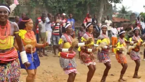 Dancers in colourful beaded outfits performing a traditional dance outdoors while onlookers watch